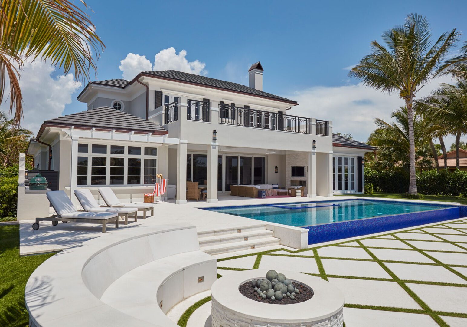 A large white house with pool and fire pit.